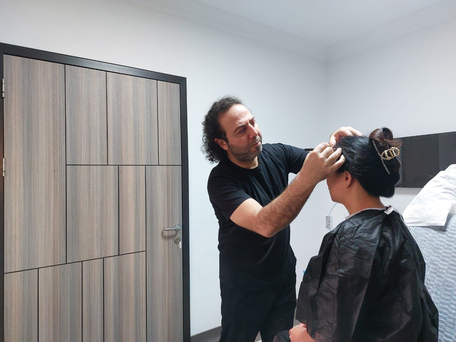 Woman on treatment table where hairline is marked off for hair transplant. 
