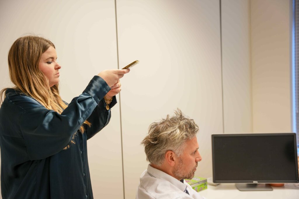 Lieselotte takes pictures of man with gray haircut for dhi hair transplant” width=